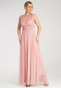 Długa, różowa sukienka z szyfonu z plisowanym gorsetem i zwiewnym dołem. Dekolt w kształcie litery V, szerokie ramiączka i podkreślona talia tworzą gładką sylwetkę.