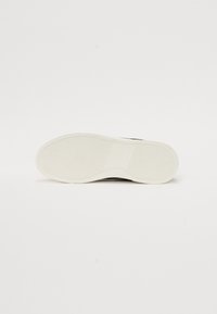 White rubber sole with textured grip, featuring a smooth brown upper. Design includes a rounded shape and subtle color contrast.