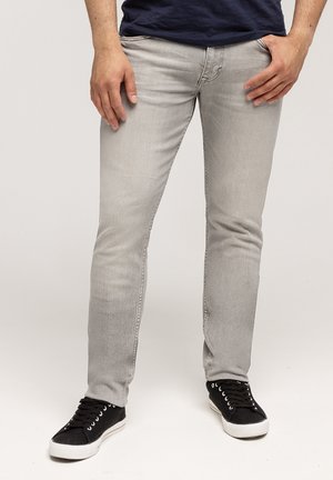 Szare, dopasowane dżinsy z denimu o gładkiej fakturze i minimalnym wyblaknięciu, w połączeniu z czarnymi, casualowymi sneakersami.