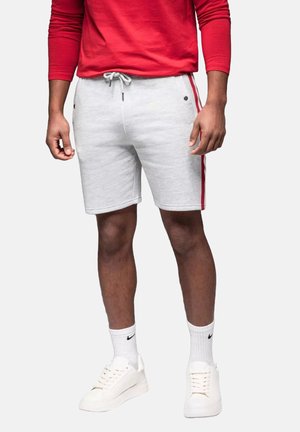 Shorts en coton gris clair avec des rayures latérales rouges, dotés d'une taille à cordon de serrage et de poches avant, associés à des baskets blanches et à des chaussettes mi-mollet.