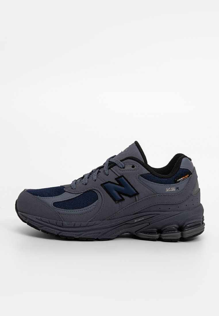 Graue Sportschuhe mit navyblauen Akzenten, aus Mesh- und synthetischen Materialien, geschwungenem Design, gepolsterter Sohle und Logo auf der Seite.
