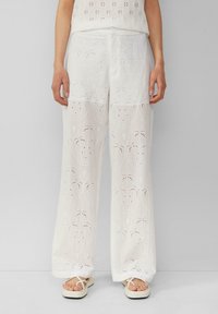 Weiße, leichte bestickte Hosen mit floralen Cut-Out-Mustern und dekorativer Naht, die einen weiten Beinanschnitt und frontale Taschen aufweisen.