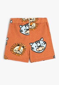 Chino orange en coton avec un imprimé de tigre et de lion. Comprend une taille élastiquée et de joyeux visages d'animaux en cartoon en noir et bleu.