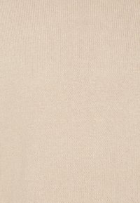 Tissu en tricot beige avec une texture fine et un motif régulier, composé d'un matériau doux et léger adapté à divers vêtements.