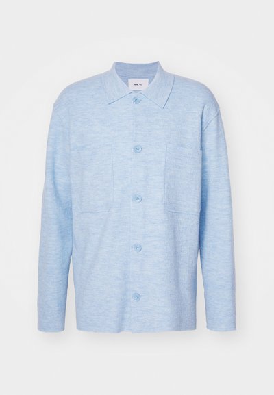 Világoskék, hosszú ujjú ing, puha anyagból készült, gallérral, két elülső zsebbel és illeszkedő gombokkal.