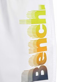 Weiße Shorts mit einem großen, orange-gelben Farbverlauf-"Bench"-Logo, das horizontale Linien und eine strukturierte Oberfläche an der Seite aufweist.