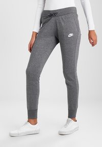 Gray sweatpants made of cotton blend, featuring a drawstring waistband, slim fit, side pockets, and a white Nike logo on the left thigh.