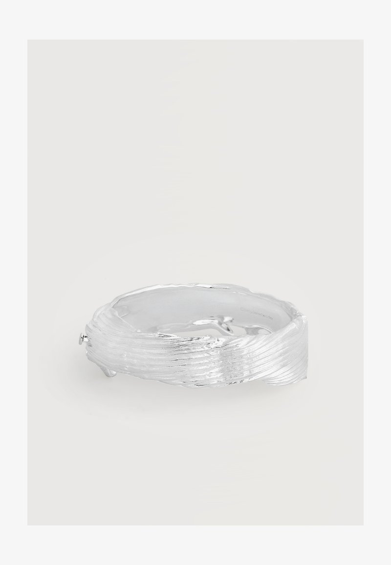 Bracelet jonc texturé en argent avec un motif ondulé nervuré et une finition polie brillante sur un fond uni.