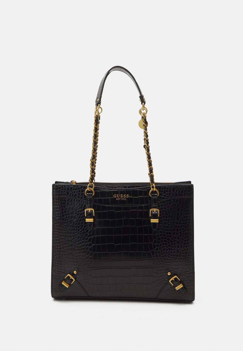 Sac cabas noir à motif crocodile avec anses chaîne dorée, boucles et logo "GUESS EST 1981" sur le devant.