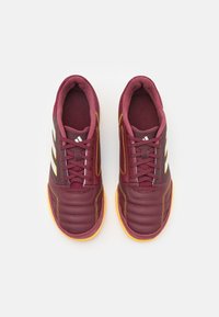 Scarpe da ginnastica bordeaux con design imbottito, dettagli gialli e strisce grigie. Punta arrotondata, lacci e suola in gomma texturizzata.