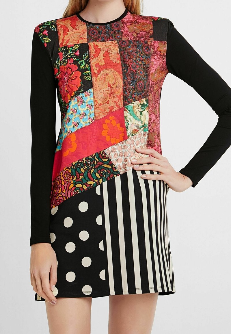 Robe à manches longues avec manches noires et corsage patchwork multicolore avec des motifs floraux, rayés et à pois sur la jupe.