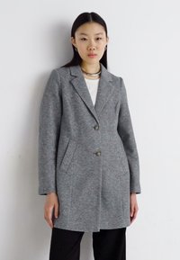 Manteau en mélange de laine gris avec col cranté, deux boutons et poches latérales. Le design présente une silhouette structurée et une texture lisse.