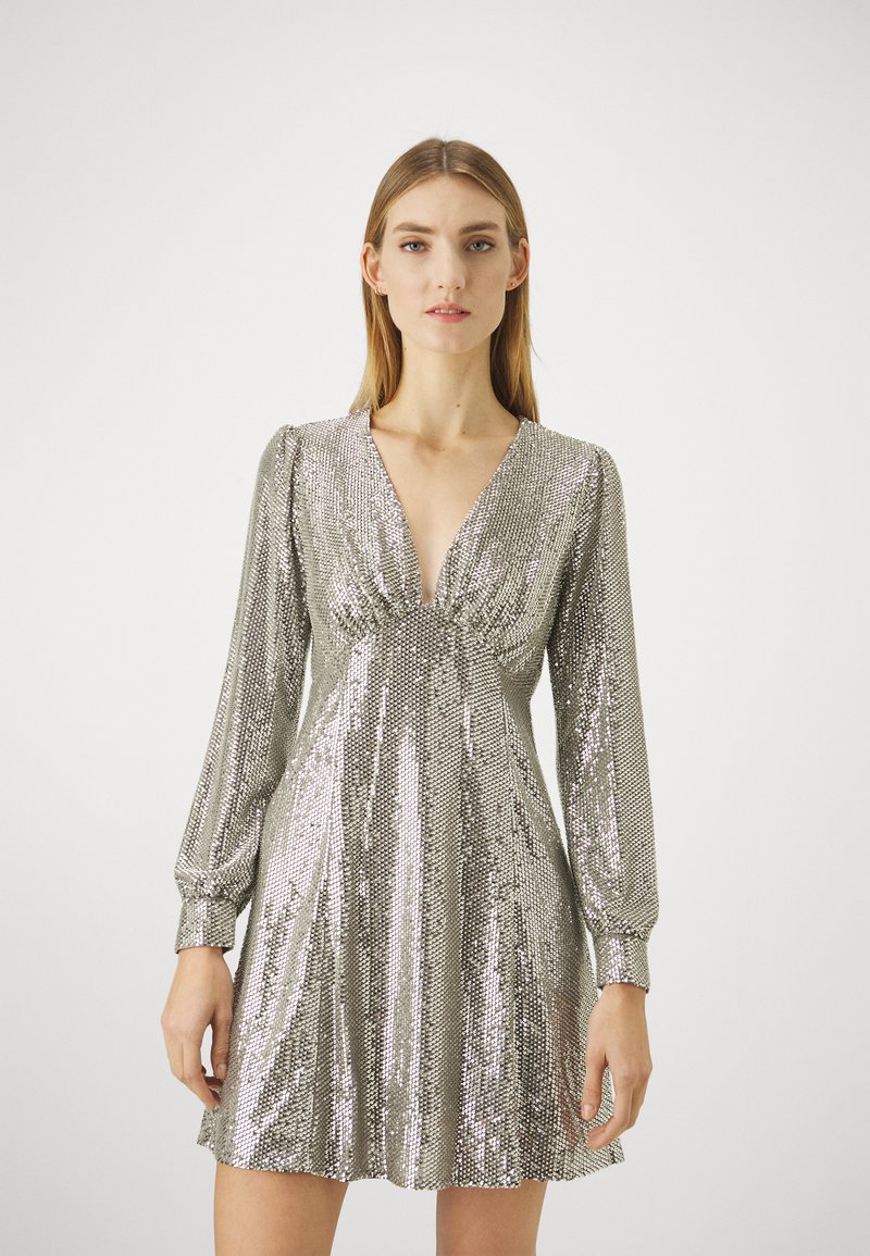Robe en sequins argentés avec un décolleté en V, des manches longues et un détail froncé à la taille ; longueur genou avec une jupe fluide.
