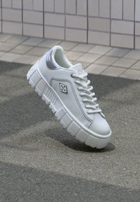 Zapatillas de plataforma blancas con parte superior de cuero suave, acentos plateados y suela de goma texturizada. Cuenta con puntera redonda y diseño con cordones.