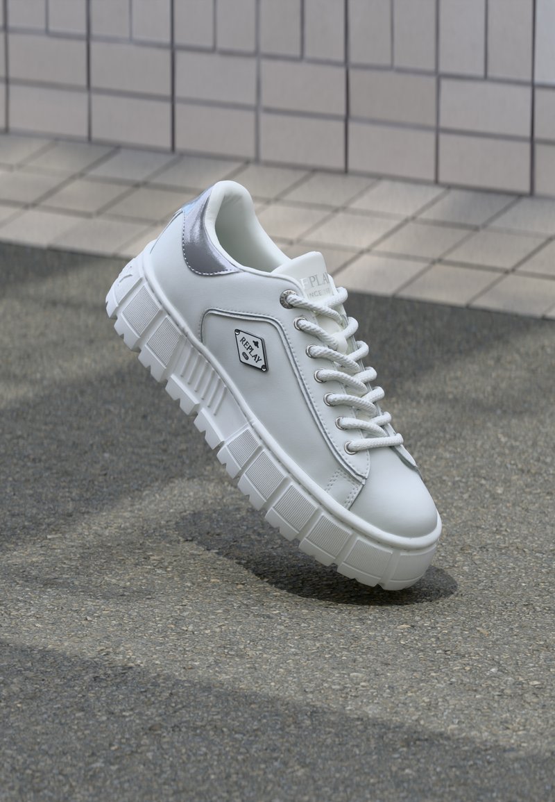 Zapatillas de plataforma blancas con parte superior de cuero suave, acentos plateados y suela de goma texturizada. Cuenta con puntera redonda y diseño con cordones.