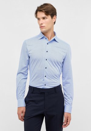 Helles, blaues, gemustertes Hemd mit langen Ärmeln, Kentkragen und dunklen Knöpfen. Kombiniert mit dunklen Hosen für einen formellen Look.