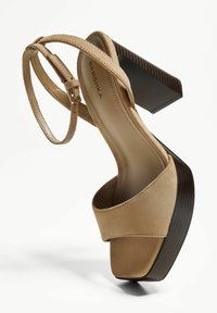 Beige suede platform sandals with a chunky dark wood heel, featuring a wide strap and adjustable ankle strap, smooth texture.