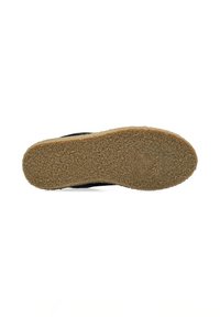 Suola nera di scarpa con superficie texture, realizzata in gomma resistente, con forma piatta e un accento in sughero di colore naturale lungo il bordo.