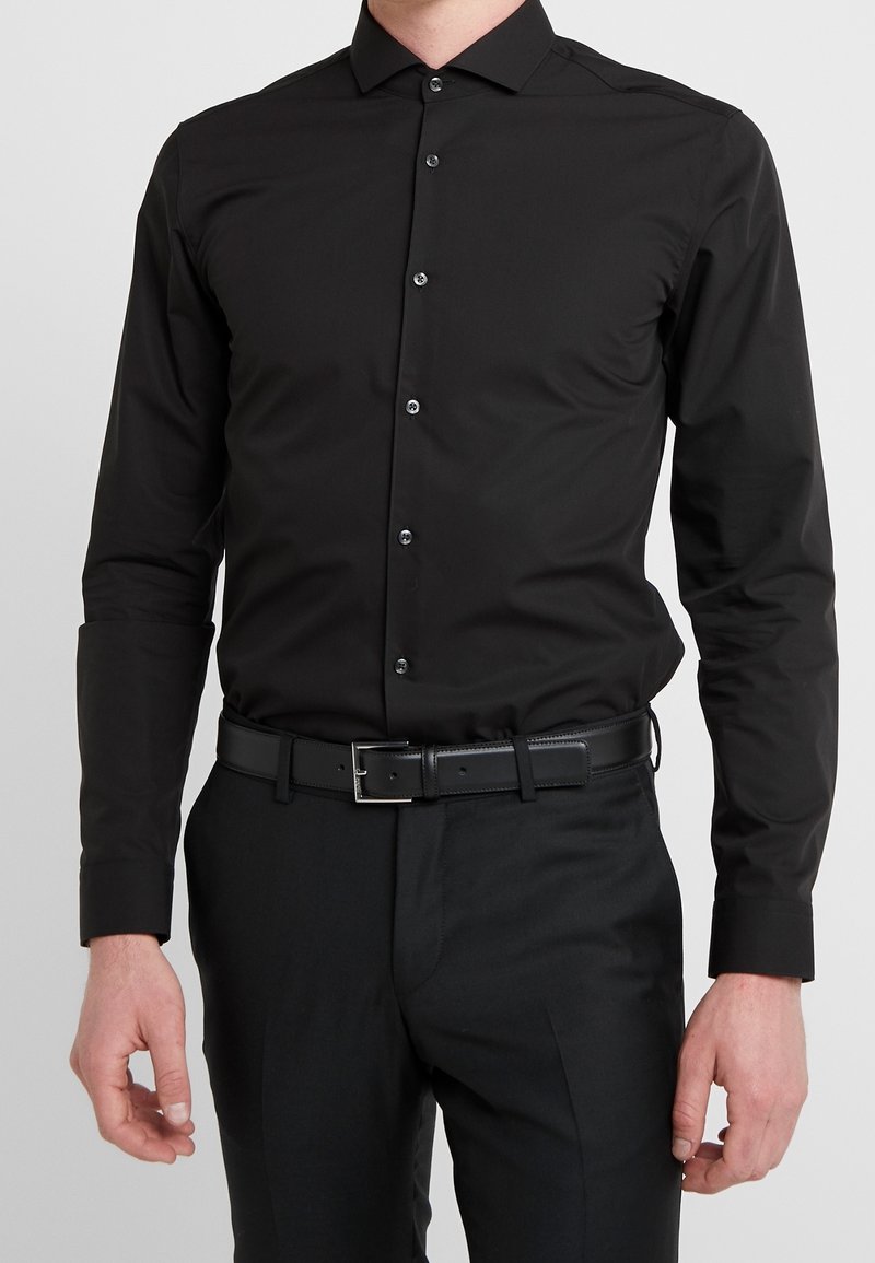 Zwart overhemd met lange mouwen, slim fit, knoopsluiting aan de voorkant, zachte textuur, gecombineerd met een zwarte riem en broek.