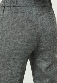 Grau karierte Hosen aus strukturiertem Stoff, mit passgenauer Form und dezenten Details an den Gesäßtaschen.