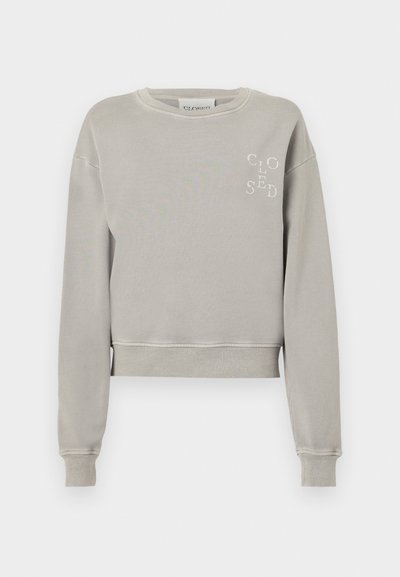 Svetlo siva skrajšana majica iz mehkega bombaža z rebrastimi manšetami, okruglim izrezom in vtisnjenim logotipom "CLOSED" na prsih.