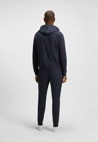 Marineblauwe hoodie en bijpassende joggingset, zachte stof, geribde manchetten en zoom, kangoeroezak, minimalistisch ontwerp, zonder opmerkelijke patronen.
