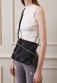 Borsa a tracolla nera in pelle con finitura texturizzata, dotata di cerniere argentate, tracolla removibile e design minimalista.
