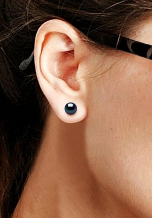 Boucle d'oreille ronde noire présentée sur l'oreille d'une personne, avec une finition brillante et un design simple, sur un ton de peau neutre.