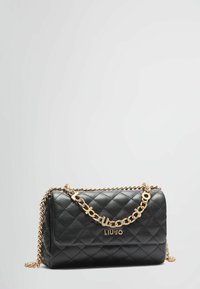 Sorte quilted taske med en guldkæde-strop, der har et logo-plakette og glat tekstur. Rektangulær form med afrundede hjørner.