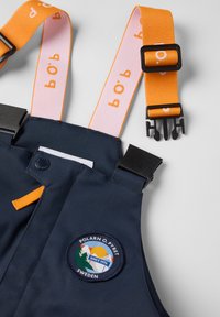 Marineblauwe outdoor bretels met oranje verstelbare banden, zwarte kunststof gespen en Polarn O. Pyret Zweden logo patch.