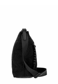 Bolso cruzado acolchado negro con correa ajustable y un tirador de cremallera trenzado en blanco y negro, mostrado desde un lado sobre un fondo blanco.