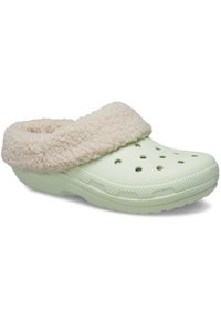 Zuecos verdes con un suave forro beige. Presentan agujeros de ventilación y una suela texturizada para mayor agarre. Forma redondeada con un diseño acogedor y cálido.