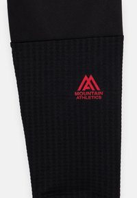 Crne sportske tajice s teksturiranim rebrastim dizajnom i crvenim logom "Mountain Athletics". Glatki gornji dio s uskim krojem.