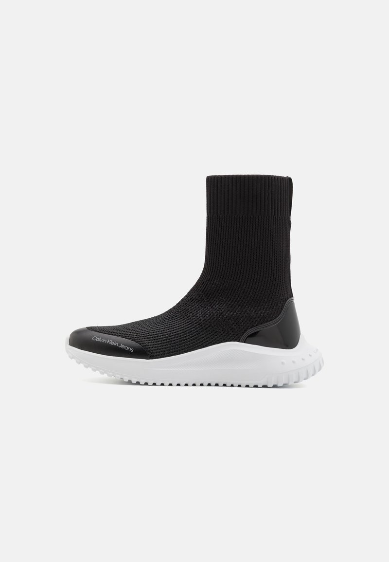 Black sock-style high-top sneaker with knit upper, white thick rubber sole, and "Calvin Klein Jeans" text on the toe cap.