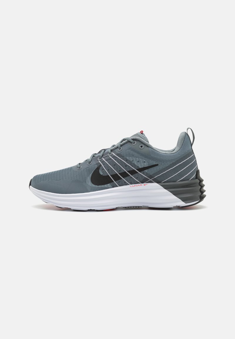 Sivé športové topánky s textúrovaným zvrškom, čiernym logom swoosh, kontrastnou bielou medzipodrážkou a červenými akcentmi na päte.