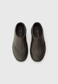 Sötétbarna slip-on klumpák barázdált felülettel és fekete talppal. A belső részén puha párnázás található rózsaszín márkázással. Tartós anyagból készült.