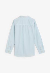 Camisa de manga larga de algodón azul claro con cuello puntiagudo, puños abotonados y un pliegue en la parte posterior para un ajuste relajado. Textura lisa, sin patrones.