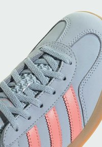 Lysblå sneakers med tekstureret læder, lyserøde takket striber og flettede snørebånd med en gummisål.