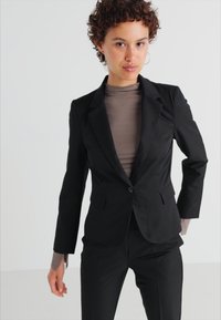 Svart skreddersydd blazer laget av glatt stoff, med enkel knappelukking, notched revers og en figursydd silhuett med lange ermer.