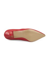 Chaussure à talon rouge vue par la semelle, avec un bout pointu et un talon aiguille court, dotée d'une semelle beige.