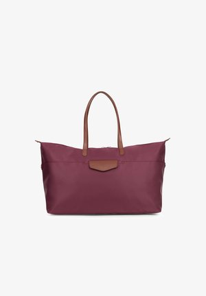 Grote bordeauxrode tote bag van gladde stof, met bruine leren handvatten en een platte voorzak met drukknoopsluiting. Met rits aan de bovenkant.