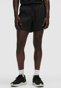 Mustat shortsit ruudullisella kuviolla, kevyttä kangasta, joustava vyötärönyöri, rento leikkaus, yhdistetty mustiin lenkkareihin.