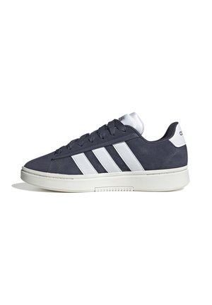 Granatowe zamszowe sneakersy mają trzy białe paski po bokach, wyściełany biały kołnierz oraz teksturowaną gumową podeszwę dla lepszej przyczepności.