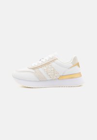 Sneaker bianca con dettagli beige e dorati, pannello testurizzato sul lato, lacci piatti e suola bianca chunky con fondo rigato.