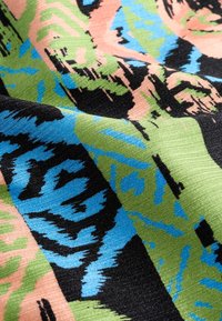 Țesătură țesută cu un model abstract în culori vibrante: negru, verde, roz și albastru, cu o suprafață ușor texturată.