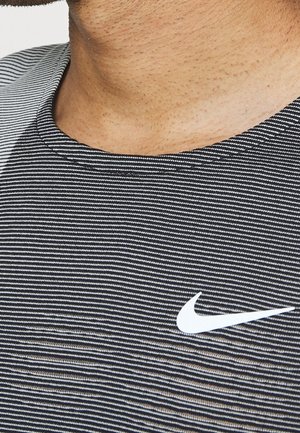 Close-up of a person wearing a black and white striped Nike shirt showing the neckline and logo on the chest.