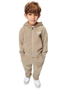 Ljust beige huva sweatshirt med framdragkedja och ficka, kombinerat med matchande sweatpants. Har ribbade muddar och enkla vita sneakers.