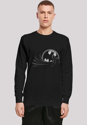 Svart bomullsgenser med grå Batman-grafikk, sirkulært logo og stiliserte bølger. Rund hals og ribbet mansjetter.