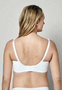 Weißer, taillierter BH mit breiten Trägern, glatter Textur und einem Haken- und Ösenverschluss auf der Rückseite; minimalistisches Design ohne Verzierungen.