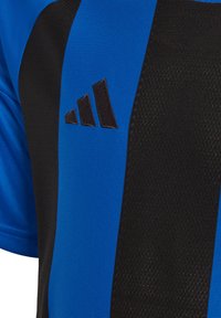 Maglia sportiva Adidas con una combinazione di colori blu e nero, tessuto testurizzato e il noto logo a tre strisce nere sulla parte anteriore.